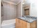 Bathroom featuring a granite countertop vanity, tiled walls, a large mirror, and a bathtub at 210 N Church St # 3606, Charlotte, NC 28202