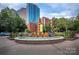 A circular brick fountain with cascading water surrounded by flowers and greenery in an urban setting at 210 N Church St # 3606, Charlotte, NC 28202