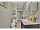 This bathroom features a marble countertop vanity, a hexagon mirror, and tiled flooring with a view towards the toilet at 530 Wilmot Trl, Gastonia, NC 28056