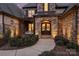 Inviting front entry featuring an arched stone surround, double doors with decorative wreaths, and lush landscaping at 17639 Stuttgart Rd, Davidson, NC 28036