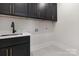 A laundry room that features painted cabinets, a sink, and a tiled floor at 3907 Plainview Rd, Charlotte, NC 28208