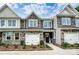 Street view of new two story townhomes with stone accents, white garage doors, and craftsman style front doors at 4236 Black Ct # 234, Harrisburg, NC 28075
