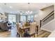 Open-concept living room featuring a dining area, staircase, and large windows at 4242 Black Ct # 233, Harrisburg, NC 28075