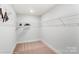 Spacious walk-in closet with wire shelving and neutral carpeting. Includes a ceiling light and room for customization at 4242 Black Ct # 233, Harrisburg, NC 28075