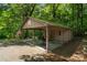 View of open carport with basketball hoop and storage with adjacent American flag in a wooded yard at 5580 Crepe Myrtle Rd, York, SC 29745