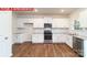 Bright modern kitchen features white cabinets, stainless steel appliances, granite countertops, and hardwood floors at 11204 Cardinal Creek Ave, Charlotte, NC 28215