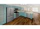 Open concept kitchen with stainless steel appliances, turquoise cabinets, island, and wood-look flooring at 121 Purple Finch Ln, Mooresville, NC 28117