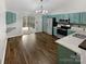 Contemporary kitchen with stainless steel appliances, vibrant teal cabinetry, hardwood floors, and sliding door access to the deck at 121 Purple Finch Ln, Mooresville, NC 28117