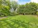 Lush green backyard with mature trees and manicured landscaping with a brick perimeter walkway at 2109 Wellesley Ave, Charlotte, NC 28207