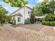 Exterior shot of a white brick home, brick driveway, manicured bushes and outdoor patio at 2109 Wellesley Ave, Charlotte, NC 28207
