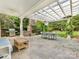 Outdoor patio with dining set, stone fireplace, grill and covered pergola surrounded by lush greenery at 2109 Wellesley Ave, Charlotte, NC 28207