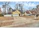 Inviting single-story yellow home with a spacious driveway, complemented by mature trees and landscaping at 2321 Heathershire Ln, Matthews, NC 28105