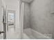 Bright bathroom with a tub shower featuring gray tile, modern fixtures, and a view to the bedroom at 281 Supernova Dr, York, SC 29745