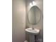 Cozy half-bathroom with a pedestal sink, round mirror, and modern lighting at 4809 Canipe Dr, Charlotte, NC 28269