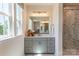 Bright bathroom featuring double sinks, gray cabinetry, a marble-tiled shower, and natural light at 5911 Wetlands Aly, Charlotte, NC 28215