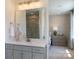 Bathroom with a bright vanity area, mirror, and doorway leading to a bedroom with neutral decor at 5911 Wetlands Aly, Charlotte, NC 28215