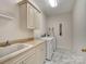 Bright laundry room featuring ample counter space, cabinetry, modern washer and dryer, and stylish flooring at 6823 Manatee Dr, Concord, NC 28025