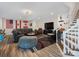 Open-concept living room with hardwood floors, a leather sofa, staircase, and a large-screen TV at 6823 Manatee Dr, Concord, NC 28025