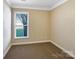 Cozy carpeted bedroom featuring a window, baseboard trim, and neutral walls at 8804 Artesa Mill Ln, Charlotte, NC 28214