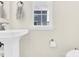 Bright half bathroom features a stylish pedestal sink, a large window, a toilet, and tiled floors at 112 August Ln, Matthews, NC 28104