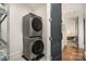 Modern laundry with stacked washer/dryer and door leading to another room, and wire rack at 1328 S Kings Dr, Charlotte, NC 28207