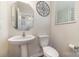 A bright half bath features a pedestal sink, toilet, and decorative mirror with a neutral color palette at 1348 Southern Sugar Dr, Charlotte, NC 28262