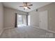 Spacious main bedroom with neutral carpet, ceiling fan, and sliding door to sunroom at 14106 Yachtsman Harbor Dr, Charlotte, NC 28278