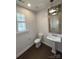 Elegant powder room featuring a pedestal sink, decorative mirror, and natural lighting at 2016 Thatcher Way, Fort Mill, SC 29715