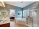 Bright bathroom with a corner tub, glass shower, and blue walls with white trim at 2024 Woodshorn Dr, Matthews, NC 28104