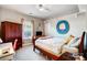 Neutral bedroom with wood bed frame, ceiling fan, and window with peach curtains at 2024 Woodshorn Dr, Matthews, NC 28104