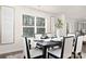 Elegant dining room with a dark wood table, white chairs, large window with blinds, and stylish decor at 5156 Fireweed Ct, Dallas, NC 28034
