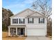 Charming two-story home featuring light gray siding, a two-car garage, and a welcoming front porch with stone accents at 5156 Fireweed Ct, Dallas, NC 28034