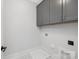 Functional laundry area with overhead cabinets, a utility sink, and tile flooring, optimizing space and convenience at 600 Campus St, Charlotte, NC 28216