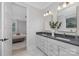 Main bathroom featuring double sinks, a gray countertop, soft lights, and an open doorway to bedroom at 600 Campus St, Charlotte, NC 28216