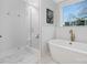 Main bathroom featuring a walk-in shower and a soaking tub, a window, and marble-style flooring at 600 Campus St, Charlotte, NC 28216