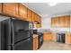 Kitchen featuring oak cabinets, vinyl floor, black appliances, and light countertops at 8583 Carolina Lily Ln, Charlotte, NC 28262