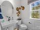 Charming half bathroom featuring a pedestal sink, round mirror, decorative wall accents, and a window with a view at 889 Regulus Ct, York, SC 29745