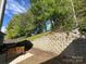 Private backyard with a retaining wall, mature trees, and cozy patio seating area at 9031 Pembroke Ct, Indian Land, SC 29707