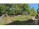 Large backyard surrounded by mature trees and a privacy fence, with a quaint patio area at 9031 Pembroke Ct, Indian Land, SC 29707