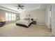Spacious bedroom featuring a tray ceiling, ceiling fan, and a large window with light-filtering shutters at 9031 Pembroke Ct, Indian Land, SC 29707