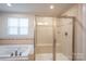 Bright bathroom features a tiled surround tub and glass-enclosed shower with a built-in seat at 10036 Paper Birch Dr, Charlotte, NC 28215
