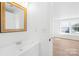 Bright bathroom featuring a wooden-framed mirror, a white vanity, and a doorway leading to a bedroom with hardwood floors at 1641 Arlyn Cir # A, Charlotte, NC 28213