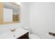 Bright bathroom featuring a wooden-framed mirror, a white vanity with bronze fixtures, and a toilet against a white wall at 1641 Arlyn Cir # A, Charlotte, NC 28213