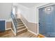 A stairway with gray stairs, metal banisters, and a blue door to a unit, showcasing access and design at 1641 Arlyn Cir # A, Charlotte, NC 28213