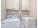 Well-lit laundry room featuring white cabinetry above the washer and dryer machines for practical storage at 4131 Nottaway Place Dr, Matthews, NC 28105