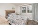 An interior view of a bedroom with a patterned comforter and pillows, windows, and hardwood floors at 4930 Crestmont Dr, Charlotte, NC 28205