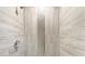 Close-up of shower featuring stylish tile work, horizontal stone-colored and vertical mosaic-patterned tiles, and shower head at 4930 Crestmont Dr, Charlotte, NC 28205