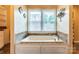 A luxurious soaking tub with a tiled platform and large window with blinds at 6108 Gold Creek Estate Dr, Hickory, NC 28601