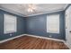 Bedroom with two windows, hardwood floors, and light blue walls at 939 Dameron Rd, Bessemer City, NC 28016
