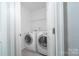 A laundry room with a washer, dryer, and storage shelf above at 9760 Springholm Dr, Charlotte, NC 28278